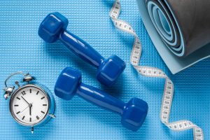 Weights between a measuring tape and yoga mat for exercise on a busy day.